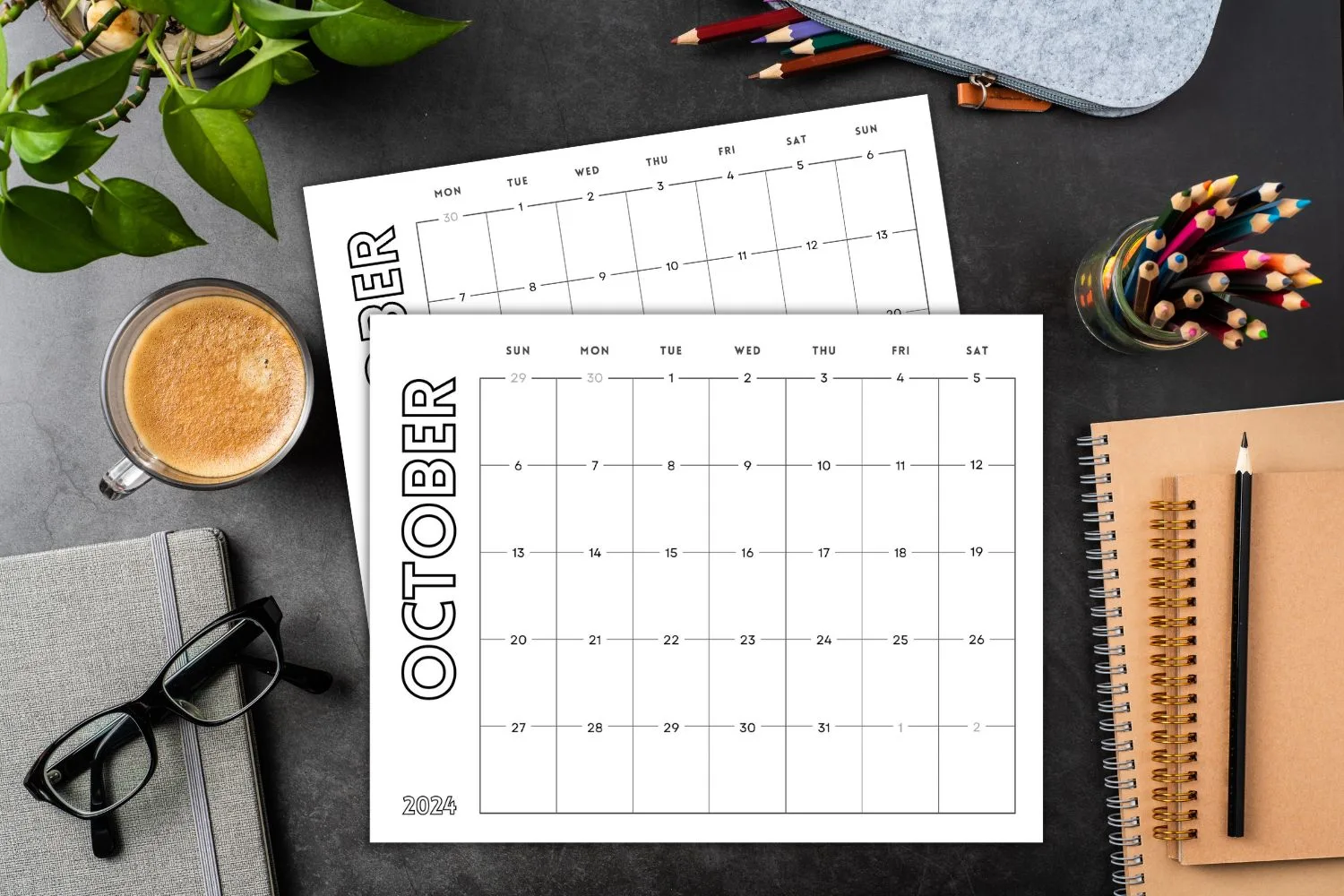 printed October calendar on black desktop with mug notebooks and glasses