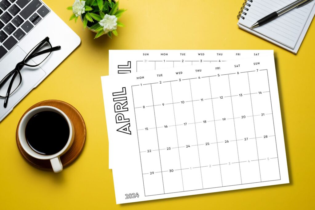printed April horizontal calendars on yellow desk with laptop and coffee