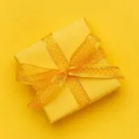 Yellow gift with yellow ribbon on yellow background