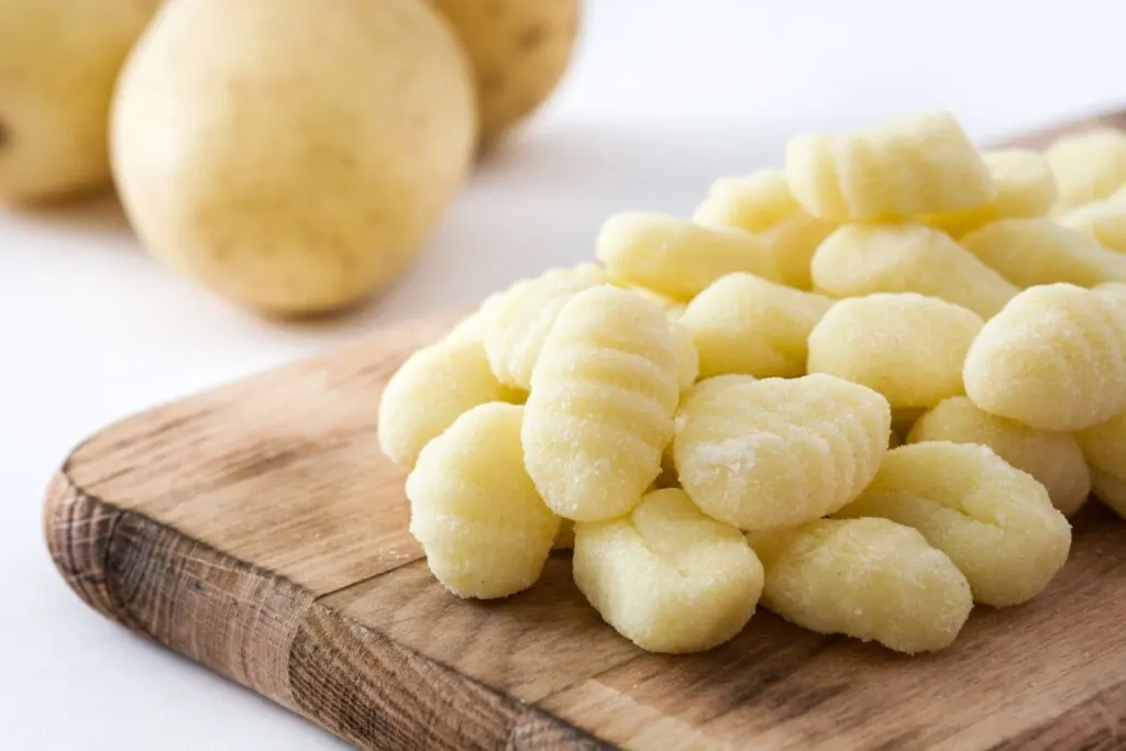 potato gnocchi on wooden board with potatoes in background